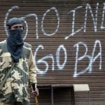 An Indian policeman stands guard near a closed shop during a curfew in Srinagar