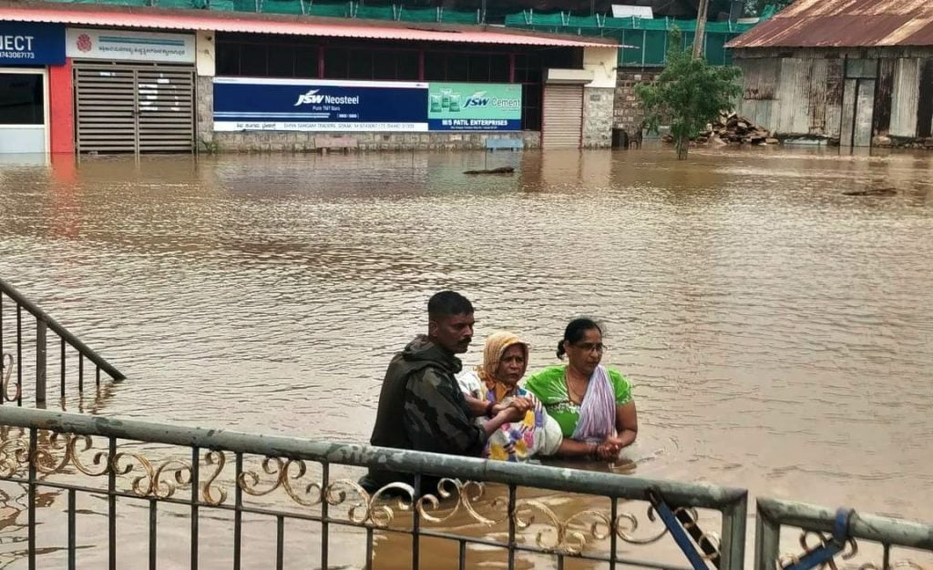 Army man assisting elderly lady in flood affected region