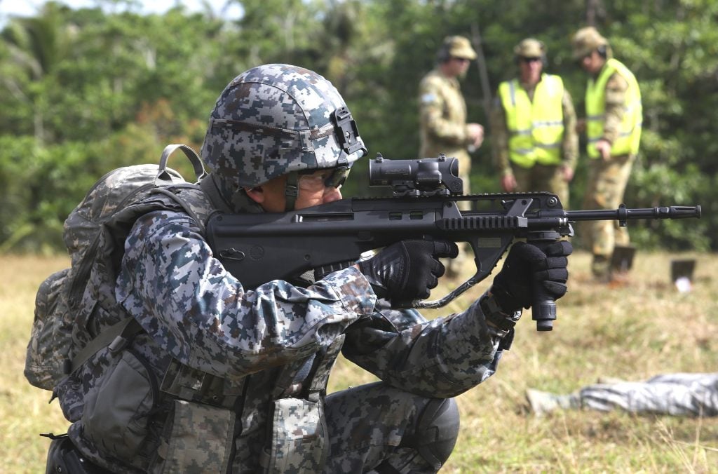 Japanese soldier fires a Steyr AUG service rifles while being coached by Australian Army,